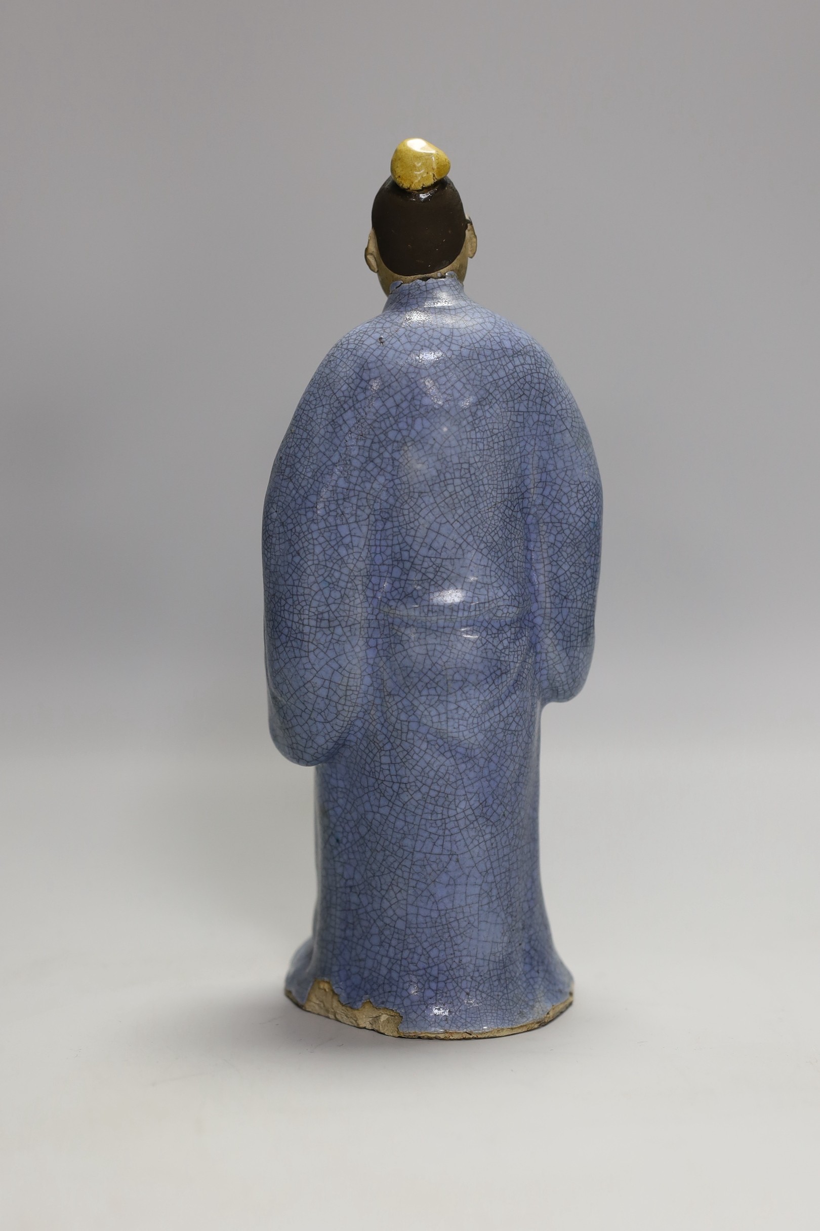 A Chinese glazed pottery figure of a man holding scrolls, early 20th century, 21cm